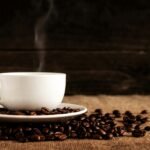 white ceramic mug and saucer with coffee beans on brown textile