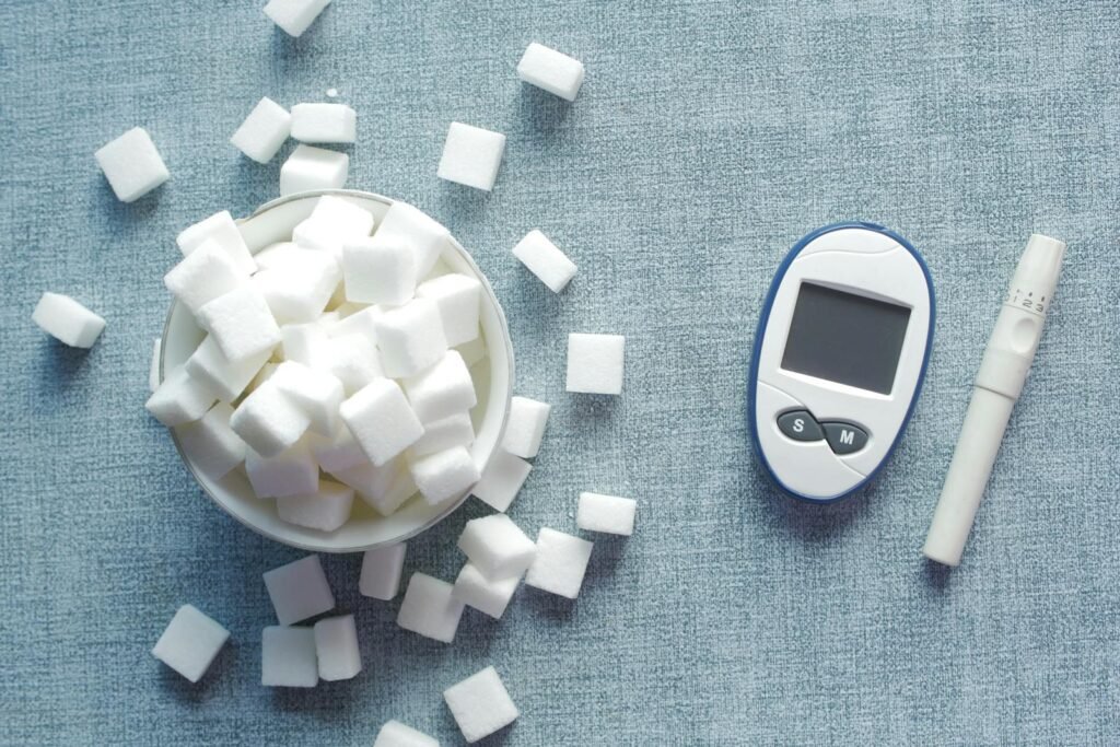 Overhead shot of a glucometer and sugar cubes representing diabetes management and sugar intake.